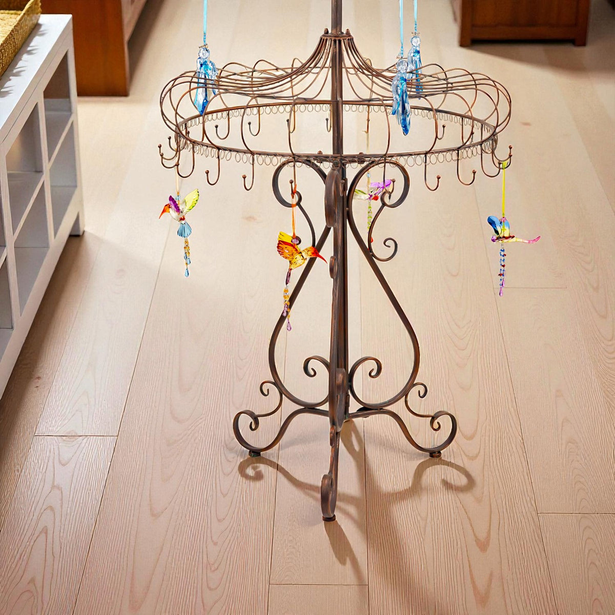 Close view of the stand’s curled metal legs and lower circular tier with colorful ornaments hanging from hooks.