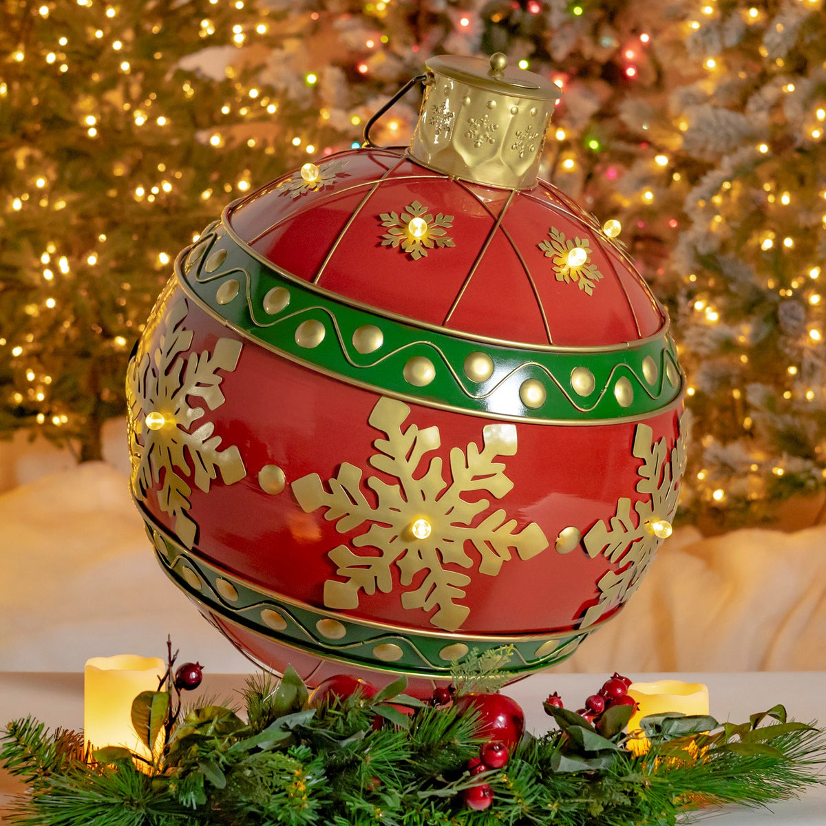 Red and gold ornament with glowing snowflake lights, shown close among holiday greenery and candles.
