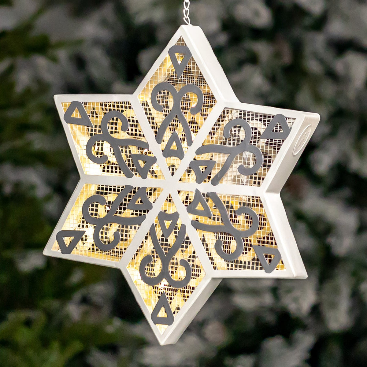 Close-up of a glowing white and silver mesh six-point snowflake ornament