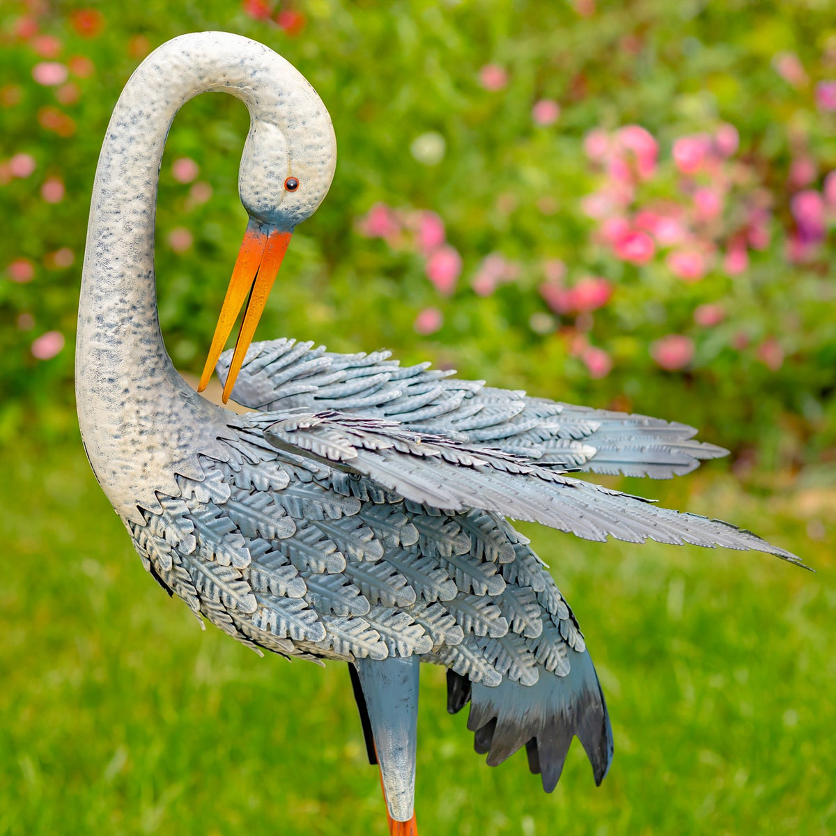 Close-up of a blue-and-white egret figurine with layered wings outdoors
