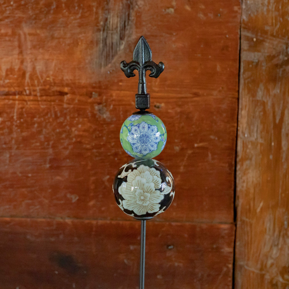 Green and dark floral ceramic spheres topped with a black iron finial