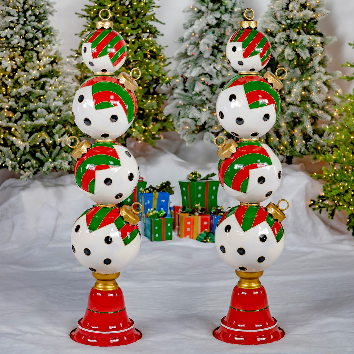 Two matching ornament towers stand side by side on the snow-covered floor in a Christmas tree display.