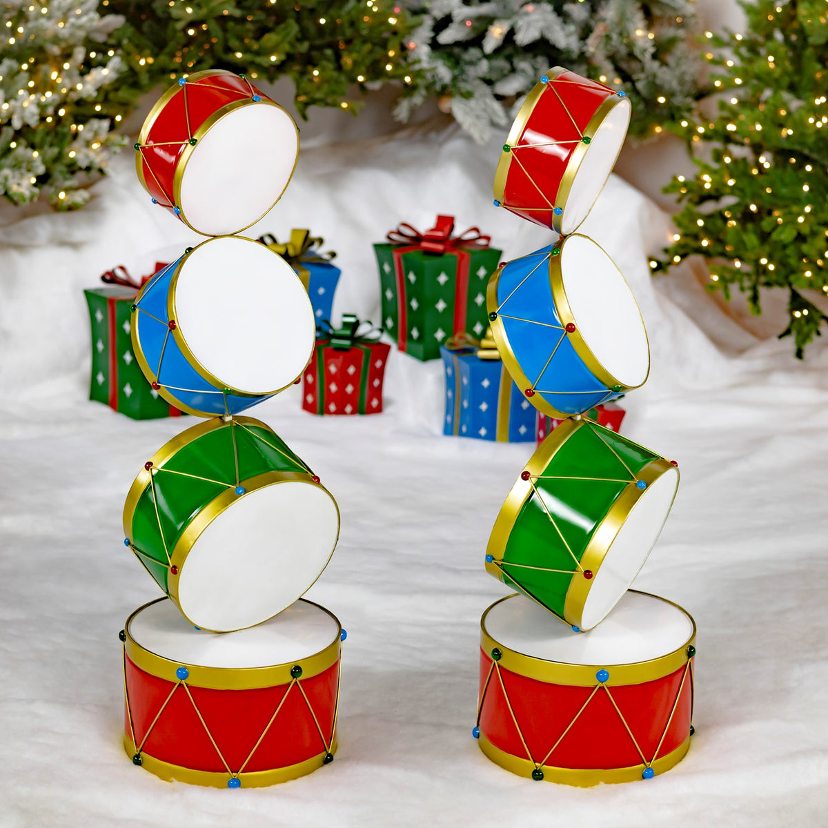 Two colorful drum towers stand side by side in a snowy holiday scene with wrapped gifts.