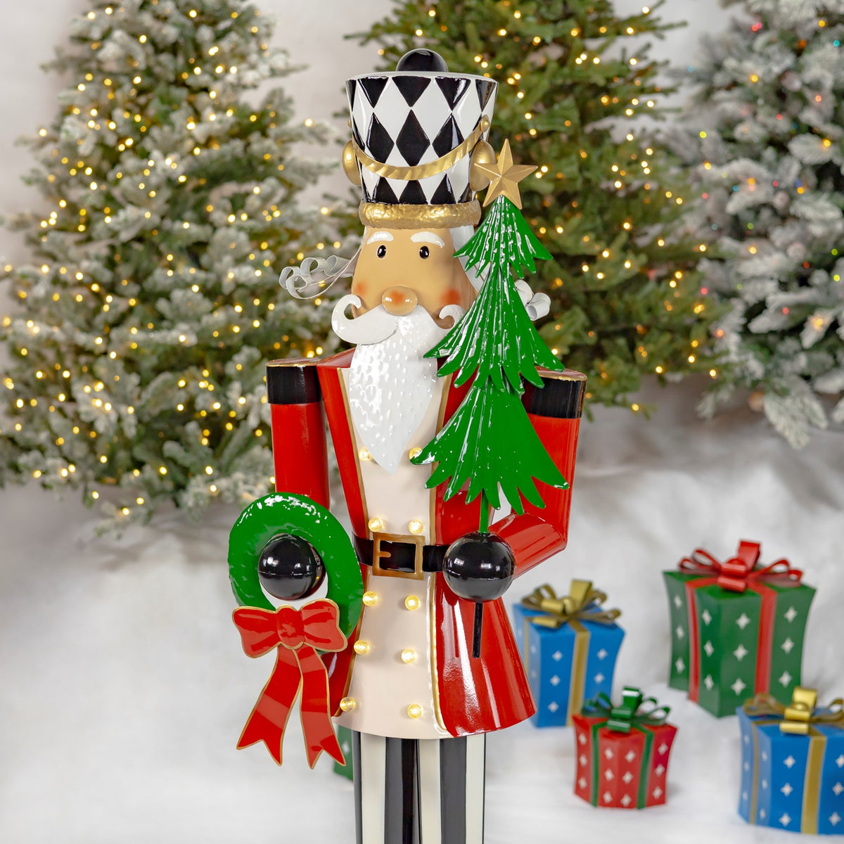 Nutcracker shown from the knees up, with a green tree and wreath against a festive backdrop.