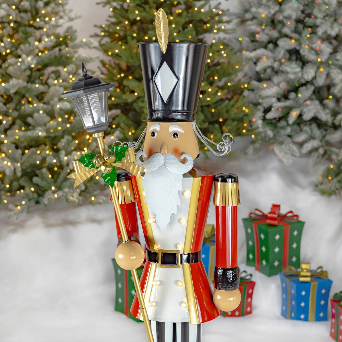 Closer view of the nutcracker’s face, tall black hat, red coat and lantern topped with a gold bow.