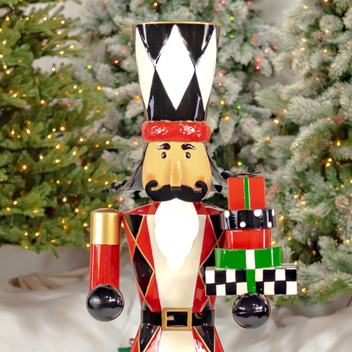 Close view of the nutcracker’s painted face, diamond-patterned hat, red jacket and stacked gifts.