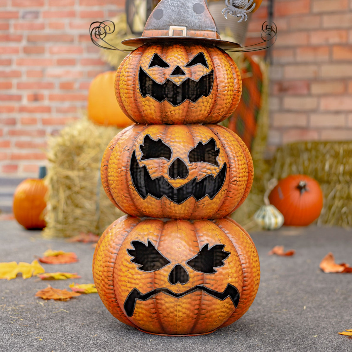 A closer view of the three stacked pumpkins shows their different jagged black faces and curled wire hat details.