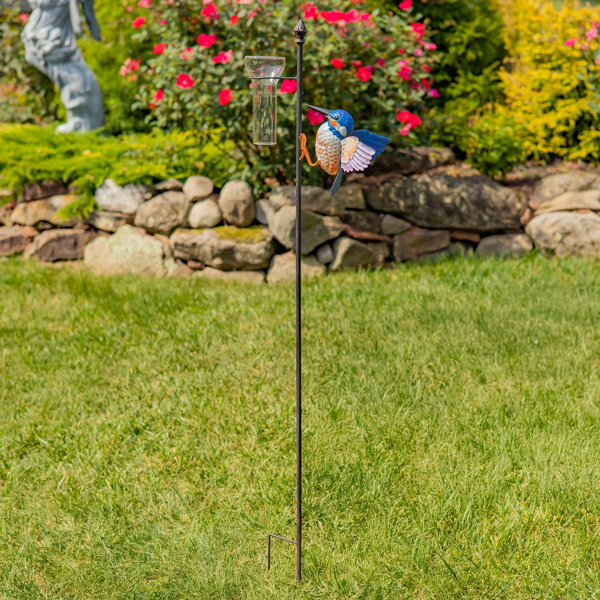 Full-height hummingbird rain gauge stake standing in a garden lawn