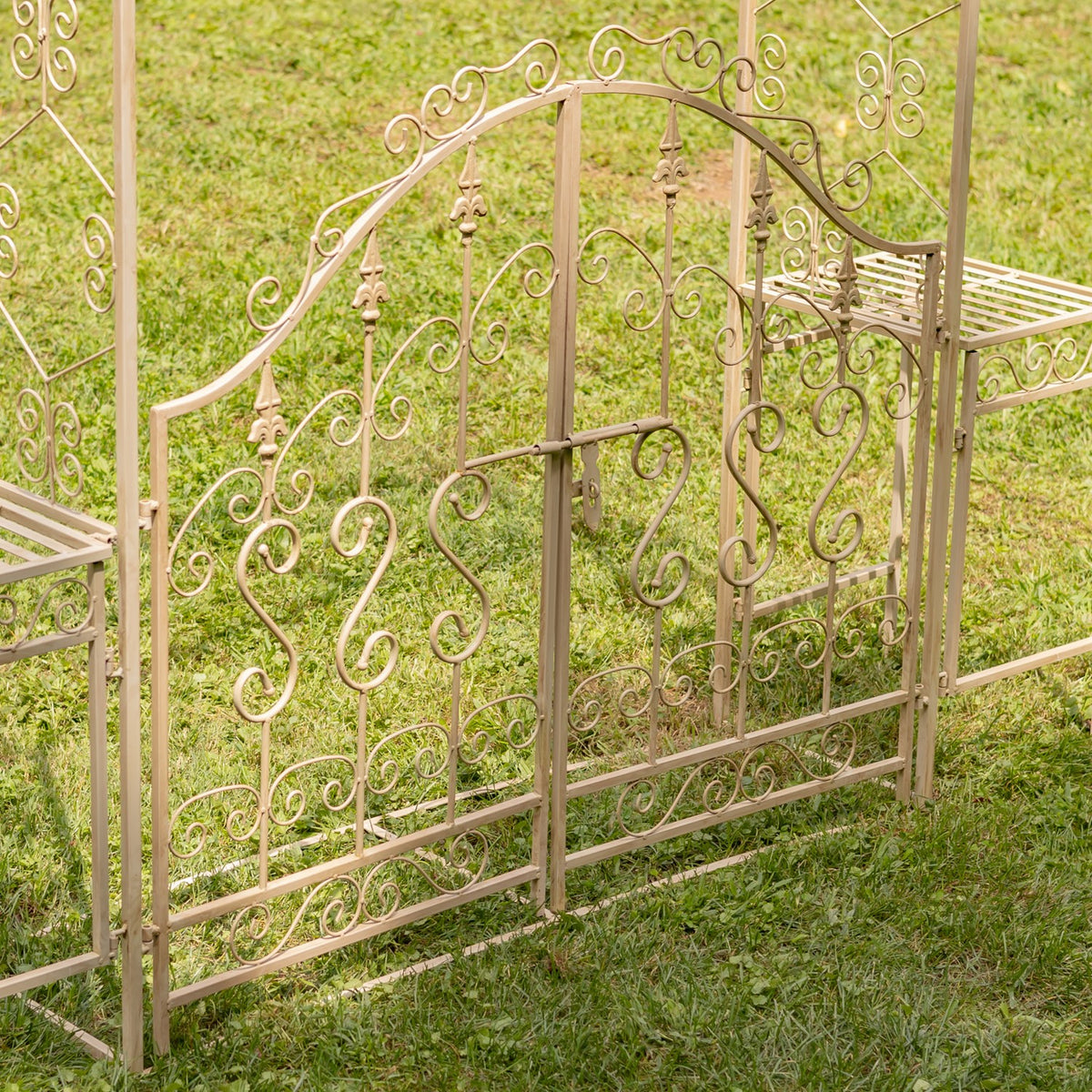Close view of the decorative iron gate scrollwork and a side plant stand