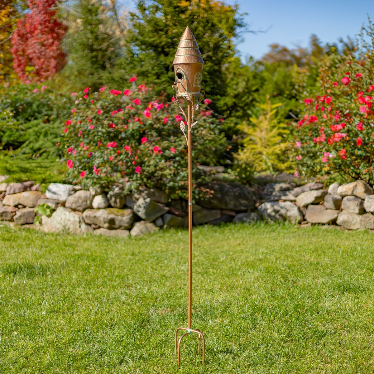 Full-length copper birdhouse stake standing in a green lawn
