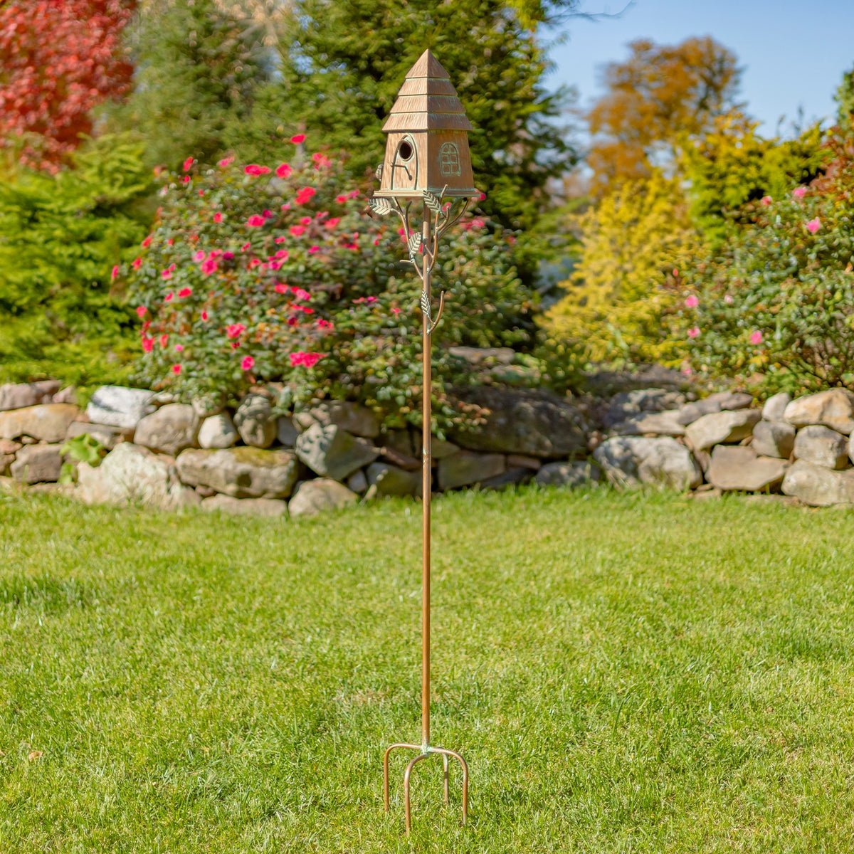 Full-length antique copper birdhouse stake standing in a garden lawn