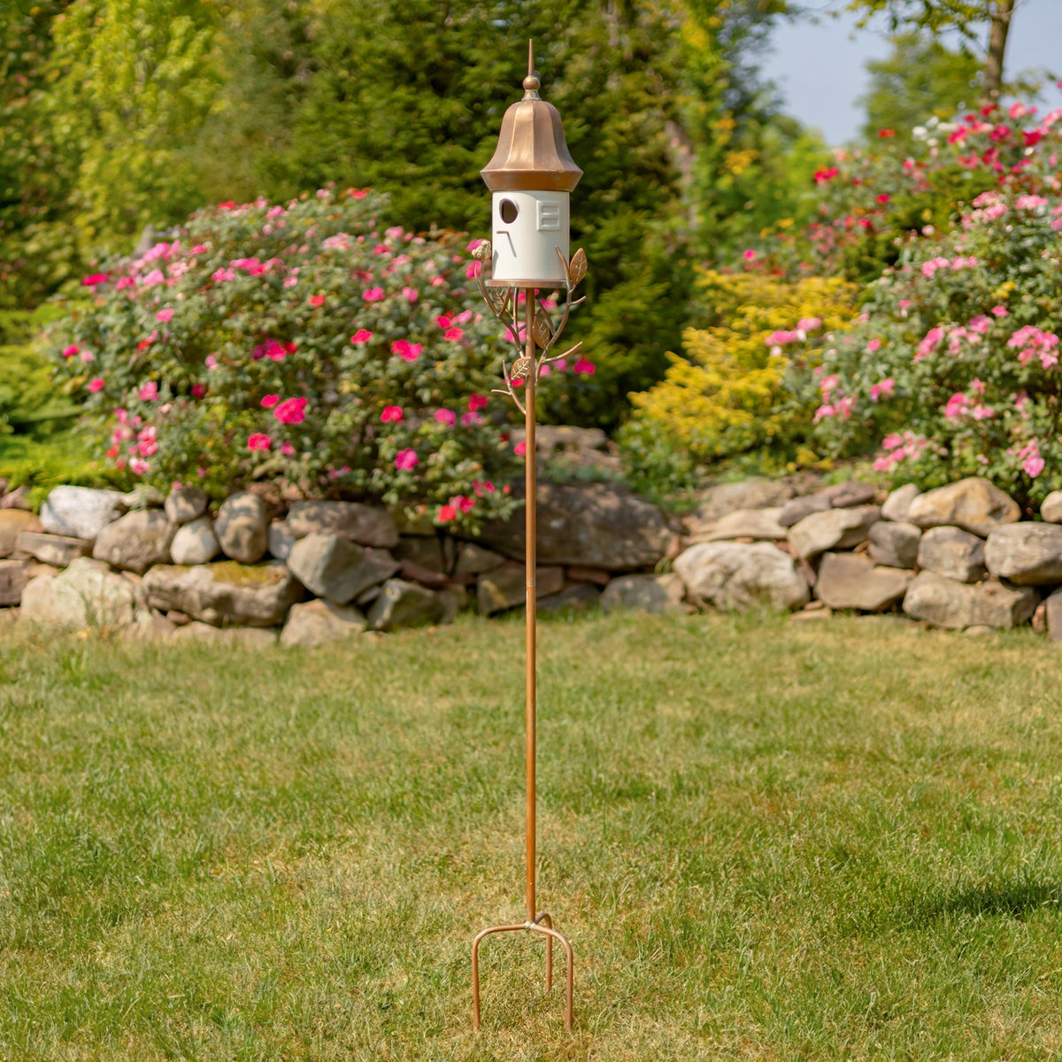 The birdhouse stake is shown from roof to pointed ground prongs in a grassy garden.