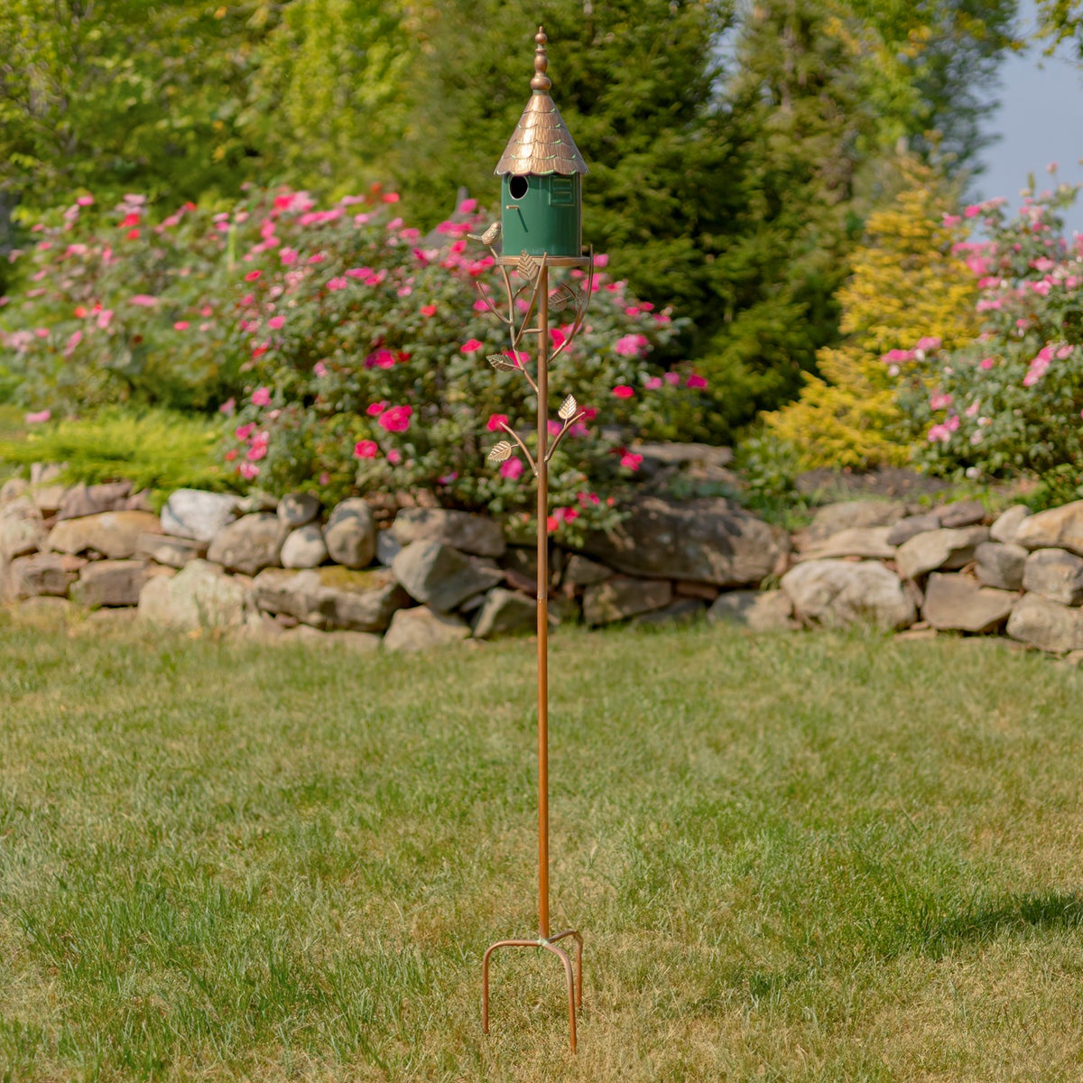 Full view of the tall birdhouse stake, including its pointed ground prongs on a lawn.