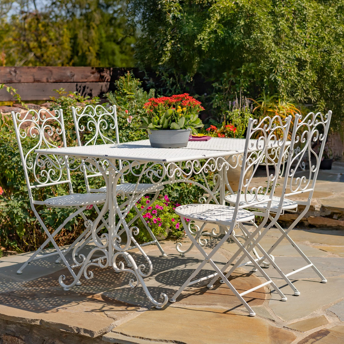 Matching metal dining set viewed from the opposite side, with a flower planter centered on the table.