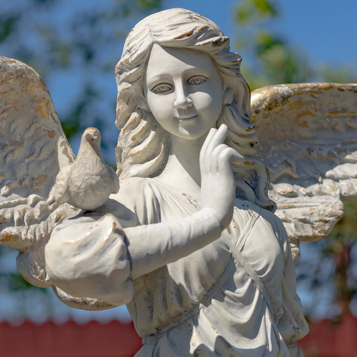 Close-up of the ivory-toned angel holding a small bird, with textured wings behind her.