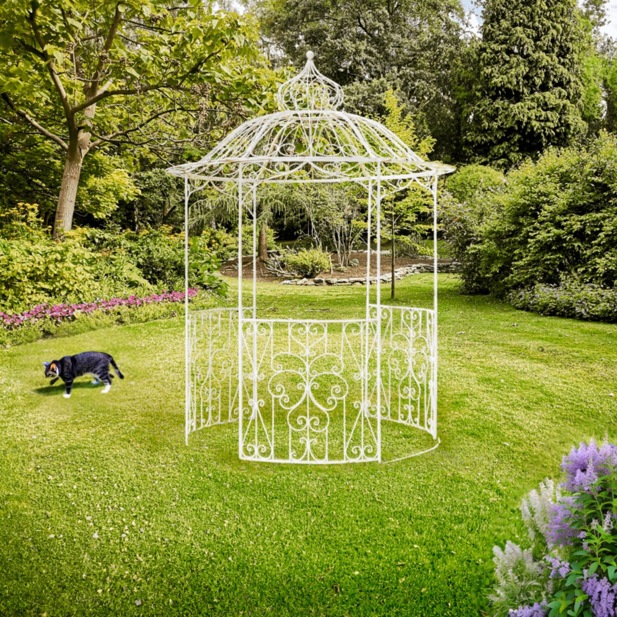 White iron gazebo standing on a green lawn in a landscaped garden