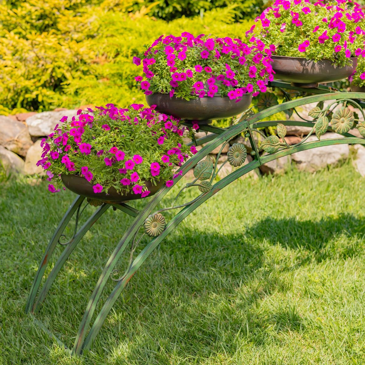 Closer angled view of the curved stand, its decorative metalwork and flower-filled bowls.