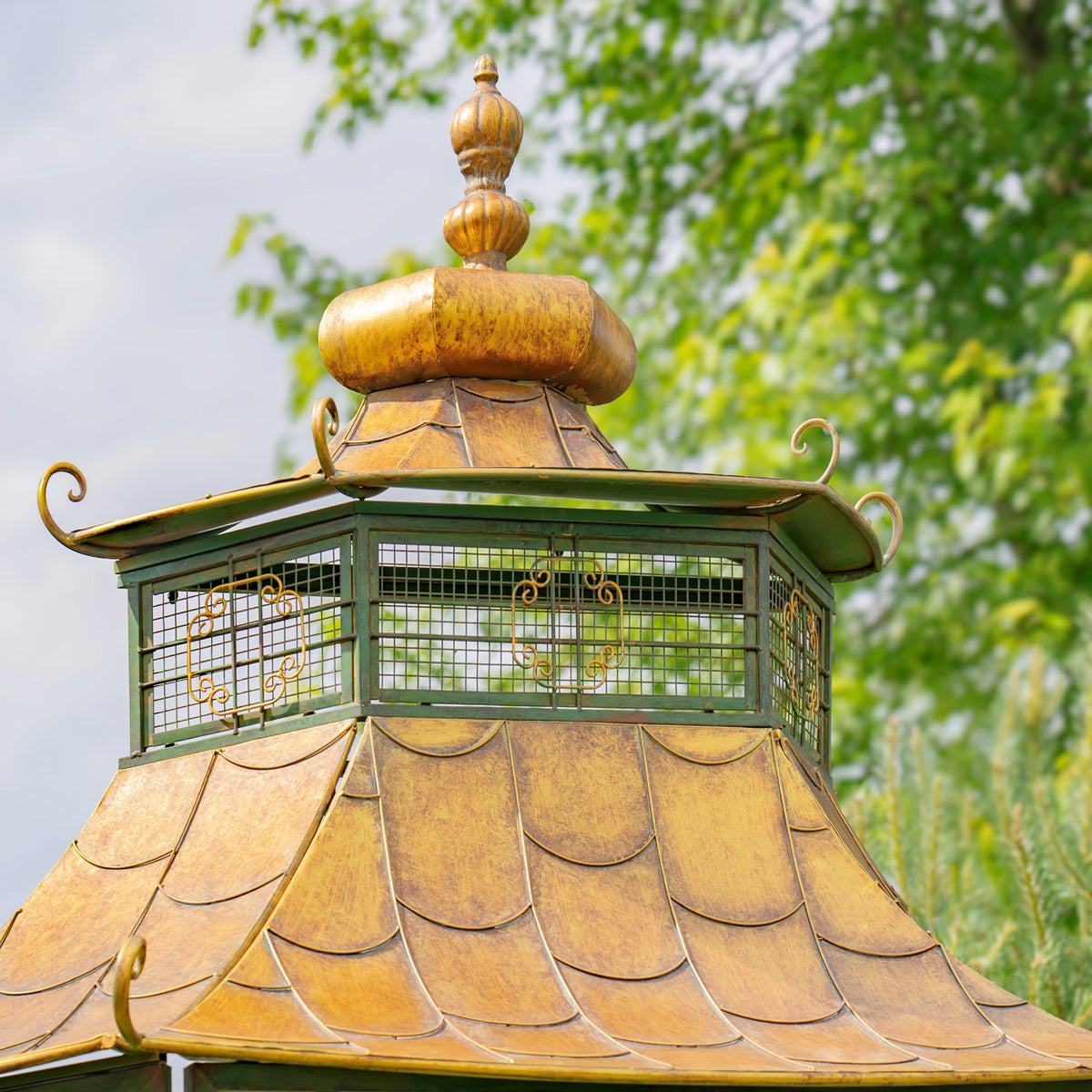 Close-up of the gate’s golden pagoda roof, green latticework and decorative finial against trees.