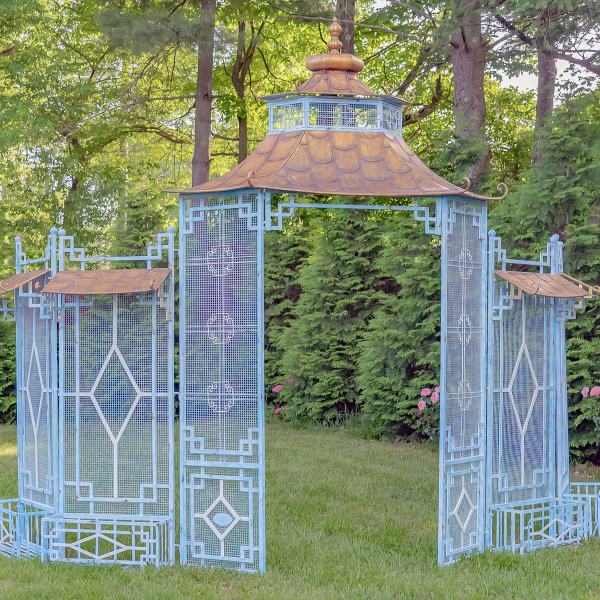 Blue pagoda-style garden gate standing on a lawn, with open central passage and matching side sections.