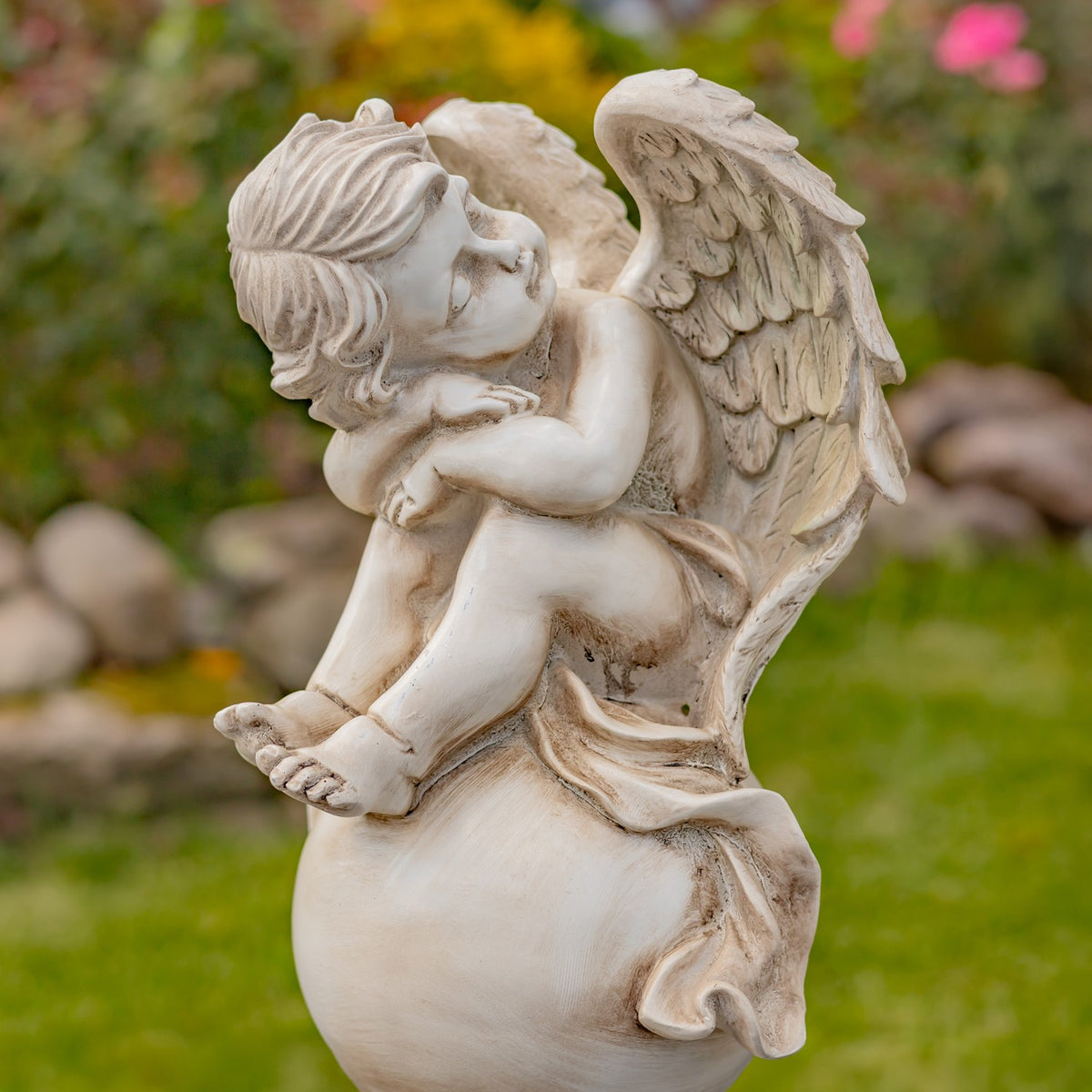 Close view of a seated cherub statue with sculpted wings