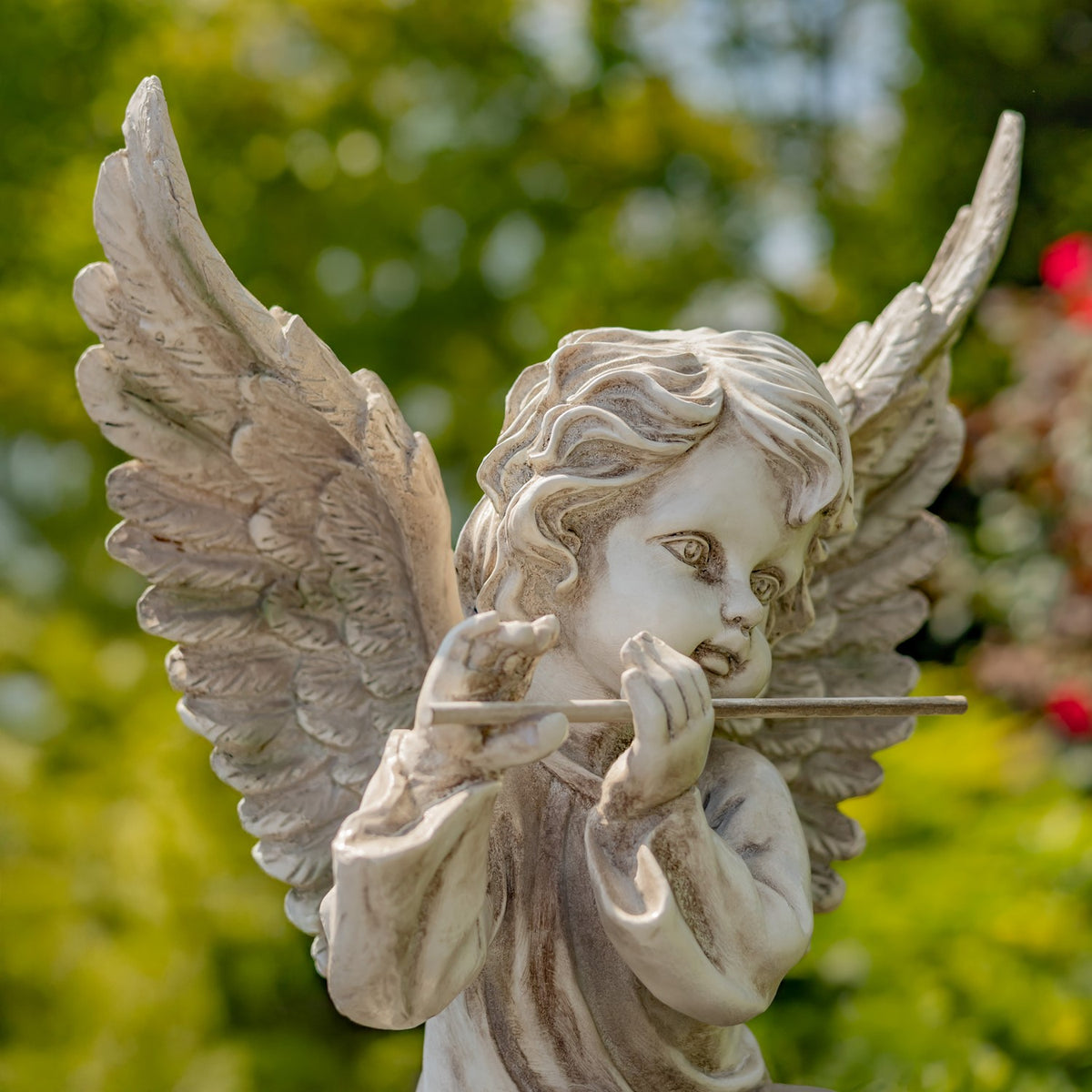 Close-up of an antique grey winged cherub playing a flute