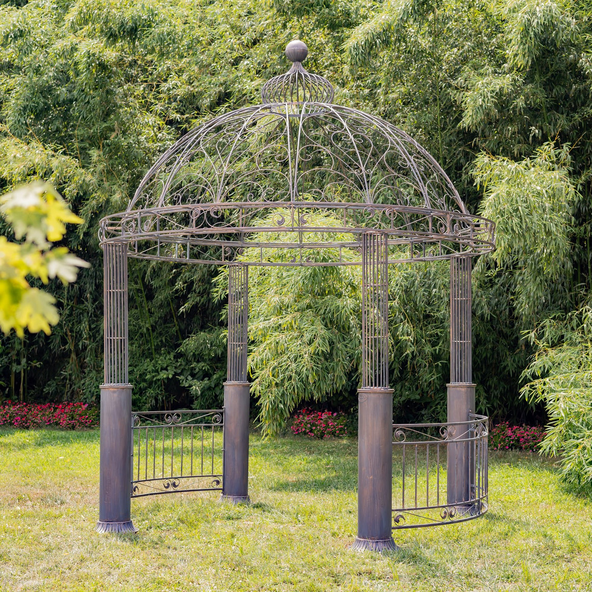 Ornate open iron gazebo with a domed lattice roof and curved railings on a lawn