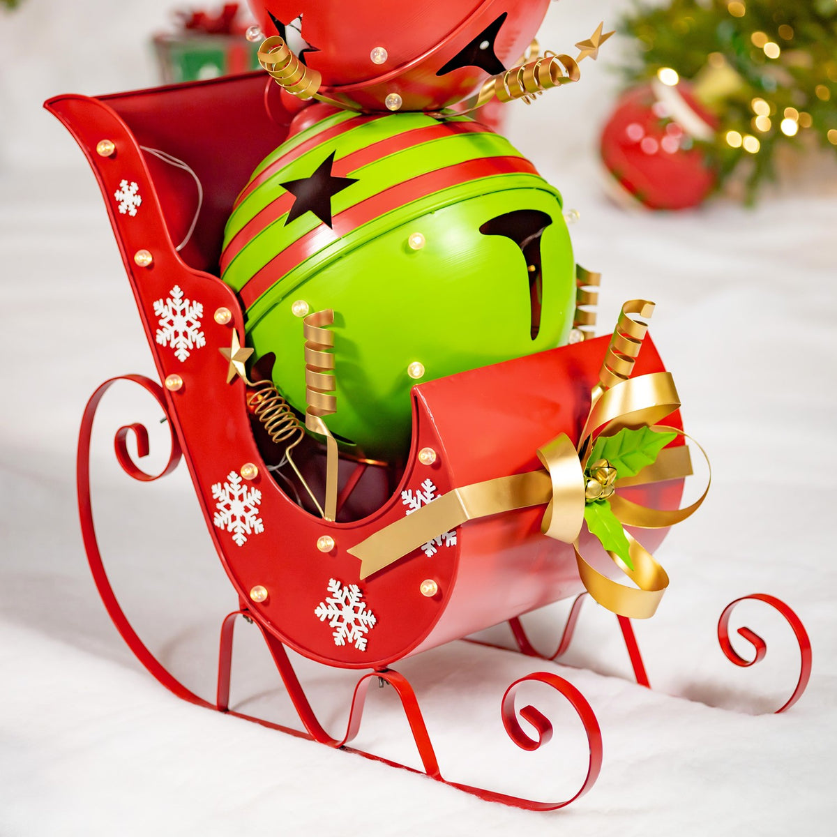 Close view of the sleigh’s curled runners, snowflake decorations, gold ribbon, and large green bell.