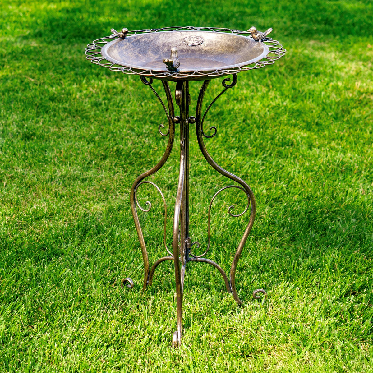 Front view of the round birdbath, showing its three-legged scrollwork stand and decorative birds around the rim.