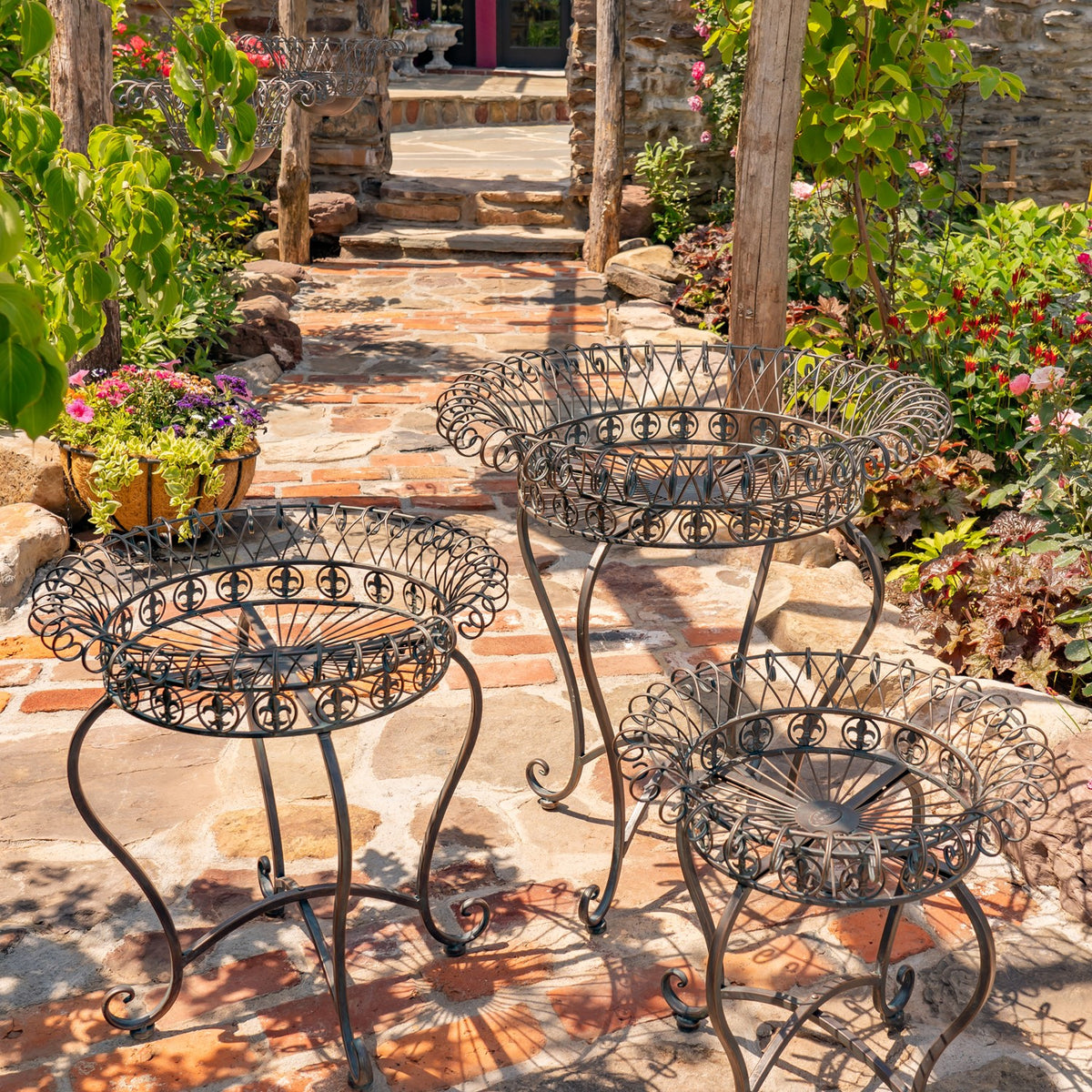 Three circular wire stands displayed on a stone patio beside a garden path.