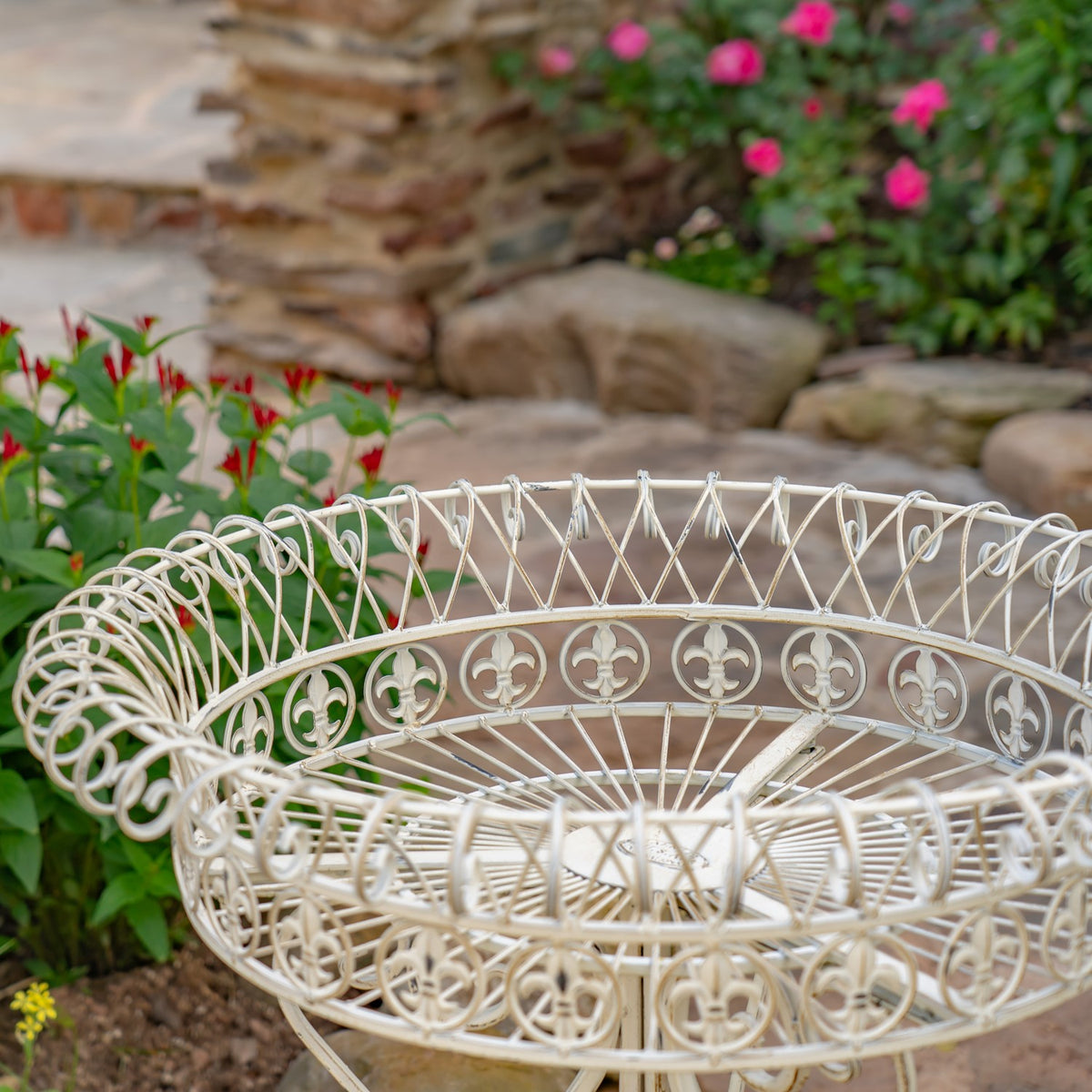 Close-up of a white wire basket with curled loops and floral patterns around its rim.