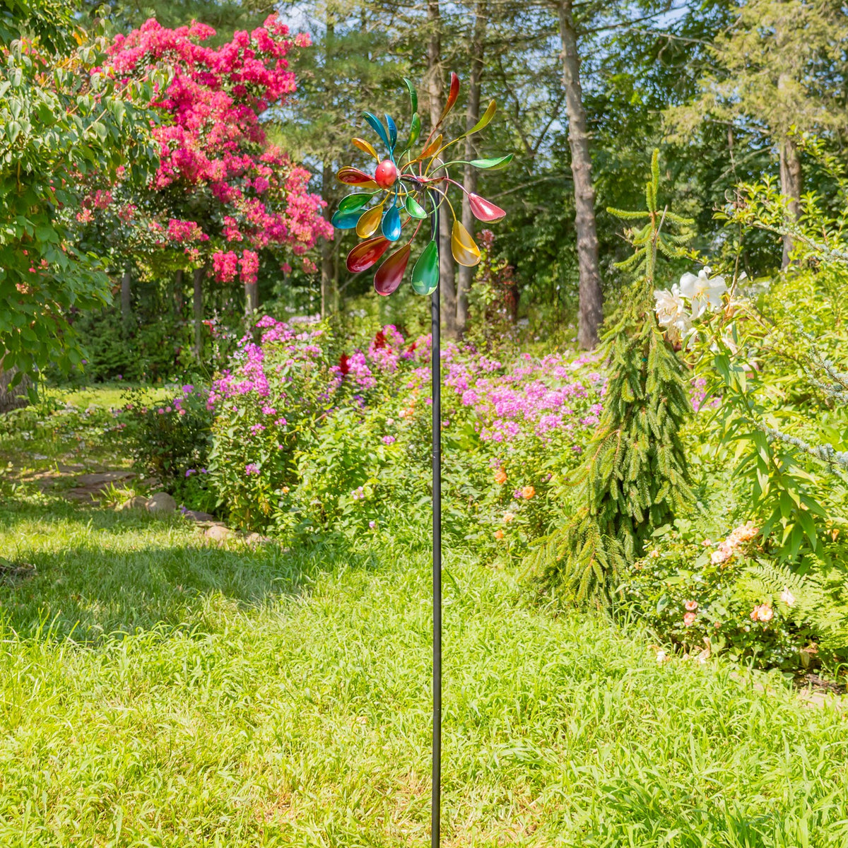 Tall multicolor windmill stake standing in a lush garden