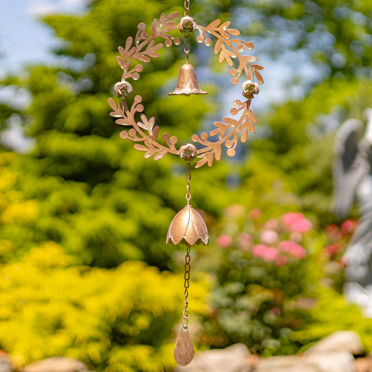 Hanging copper-toned wreath with a small bell inside the ring and two ornaments suspended below.