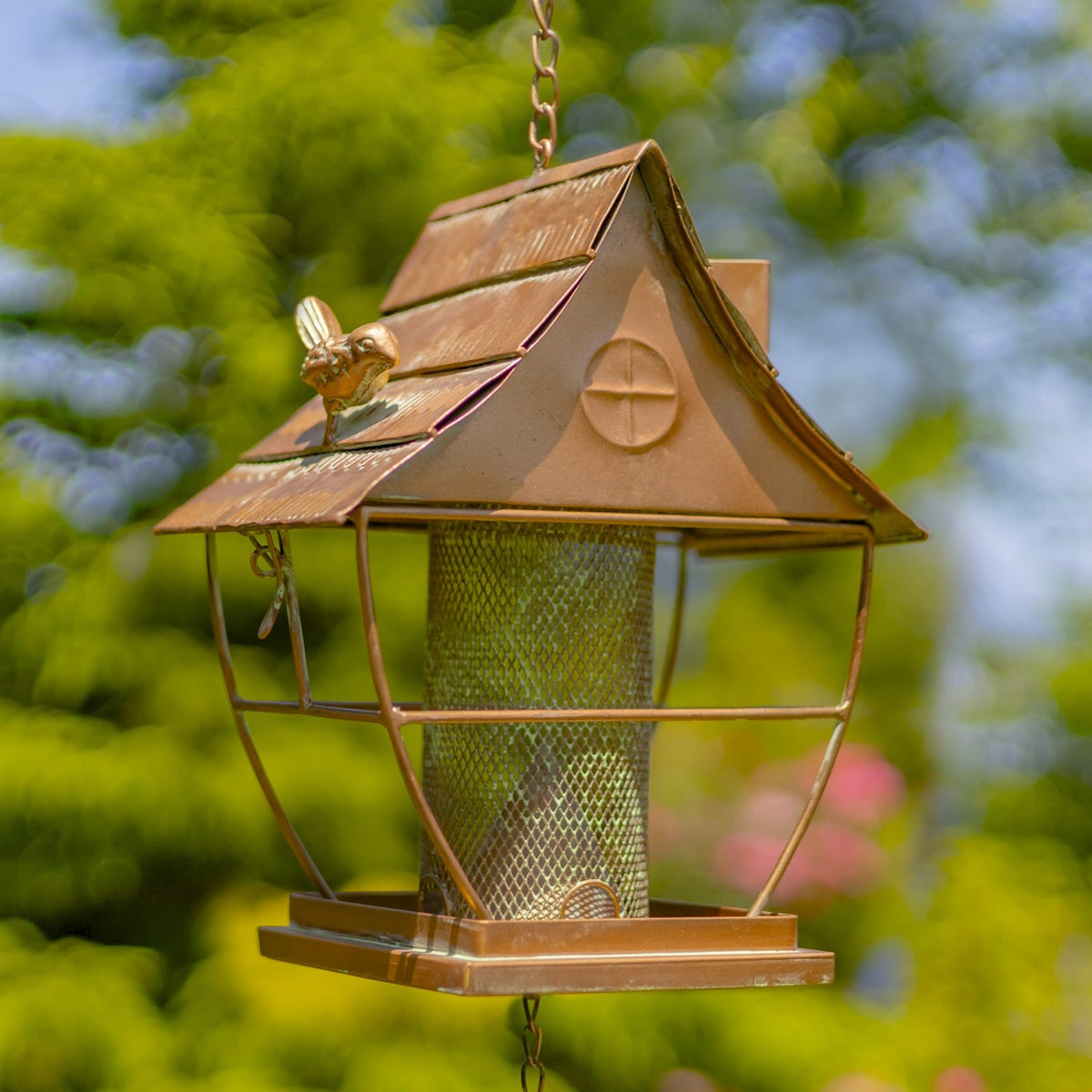 Close view of the feeder’s peaked roof, small bird ornament, mesh hopper, and surrounding frame.