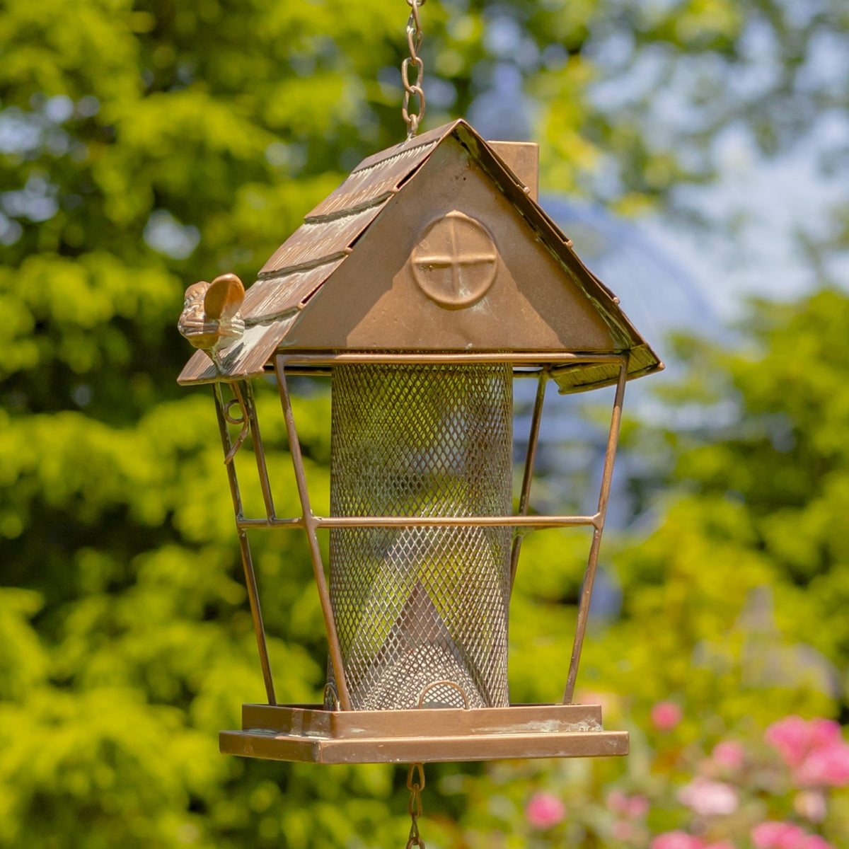 Close view of mesh seed cylinder beneath the feeder's peaked metal roof