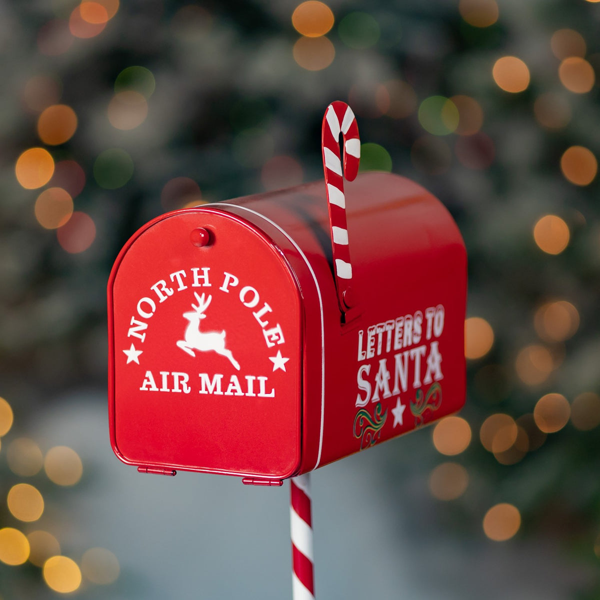 Close-up of a red mailbox with a candy cane striped post and festive graphics.
