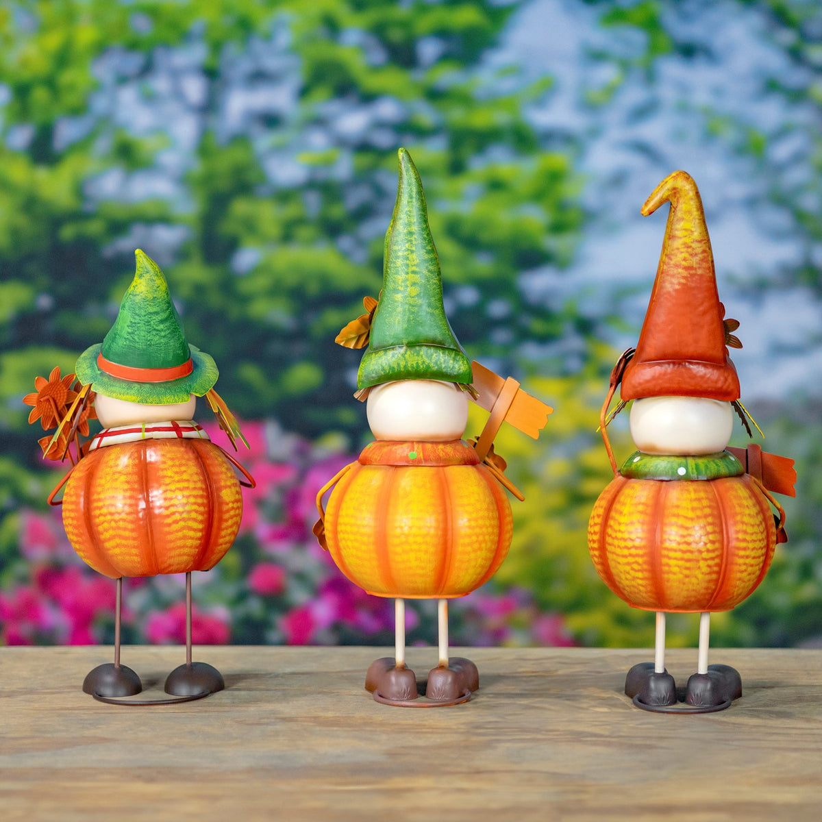 Three pumpkin scarecrows are shown from behind, revealing their hats, pumpkin bodies and metal legs.