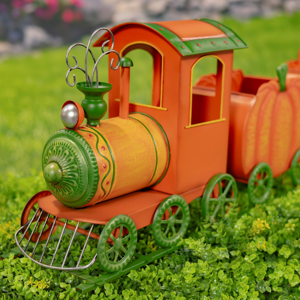 Close view of the train engine, showing its decorative green wheels, metal grille and curled ornament.