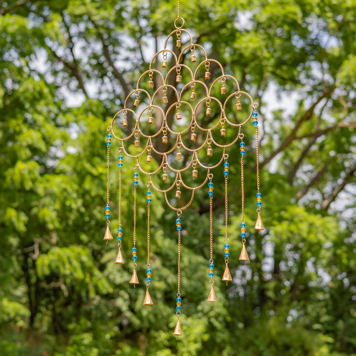 Gold ring-pattern wind chime with blue and turquoise bead strands, shown outdoors.