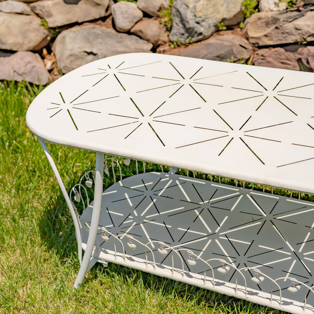 Close view of the antique white table's patterned top and lower shelf