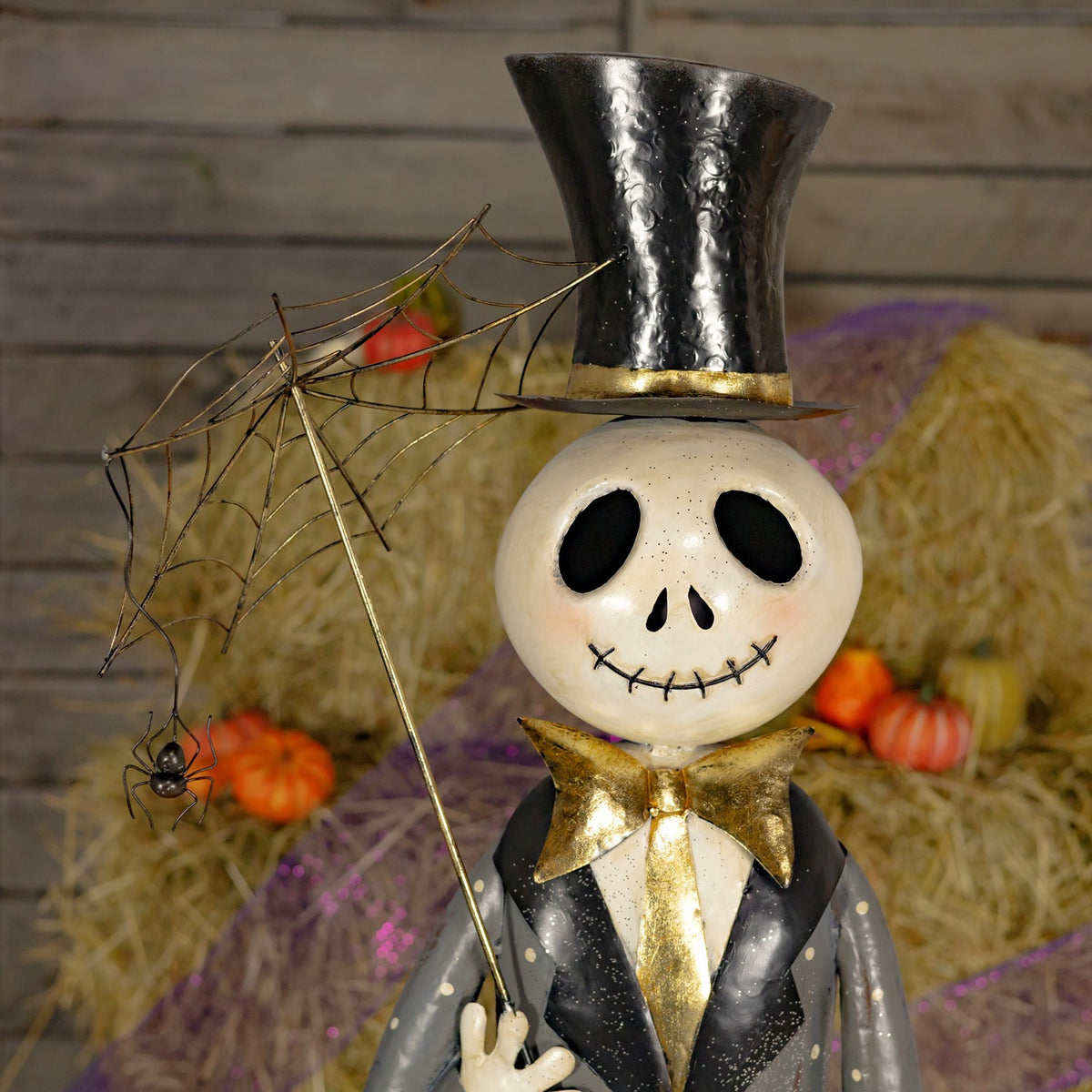 Close-up of the skeleton's grinning face, top hat, gold bow tie, and umbrella with a dangling spider.