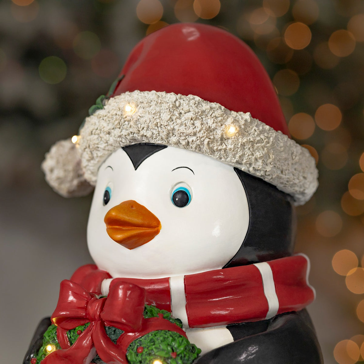 Close view of the penguin's face, red Santa hat, striped scarf, and glowing hat trim.
