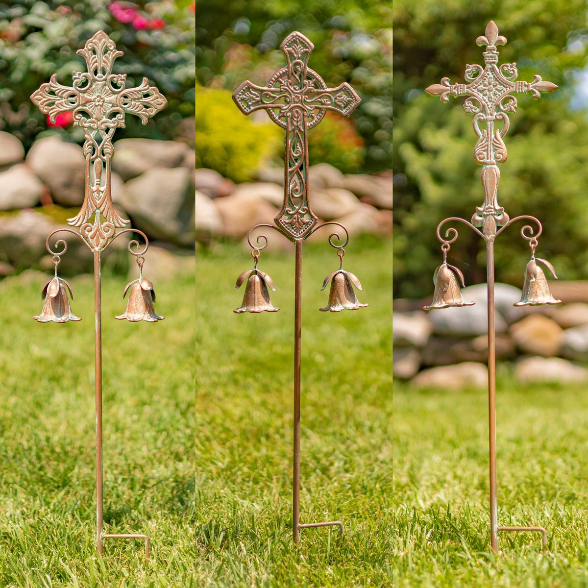 Three different decorative cross garden stakes with hanging bells stand together in a grassy garden.