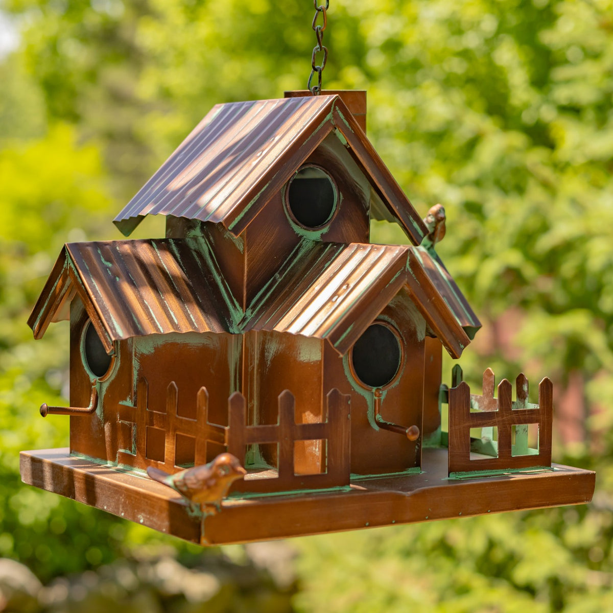 Angled view of the multi-roof birdhouse, showing several round openings, fence details, and its hanging chain.