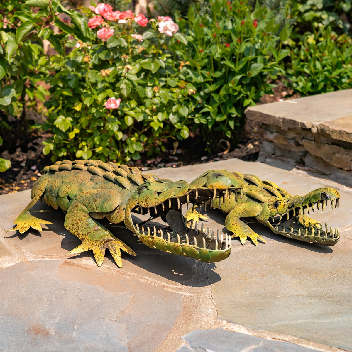 Two open-jawed alligator decorations are shown from the opposite side on a sunlit patio.