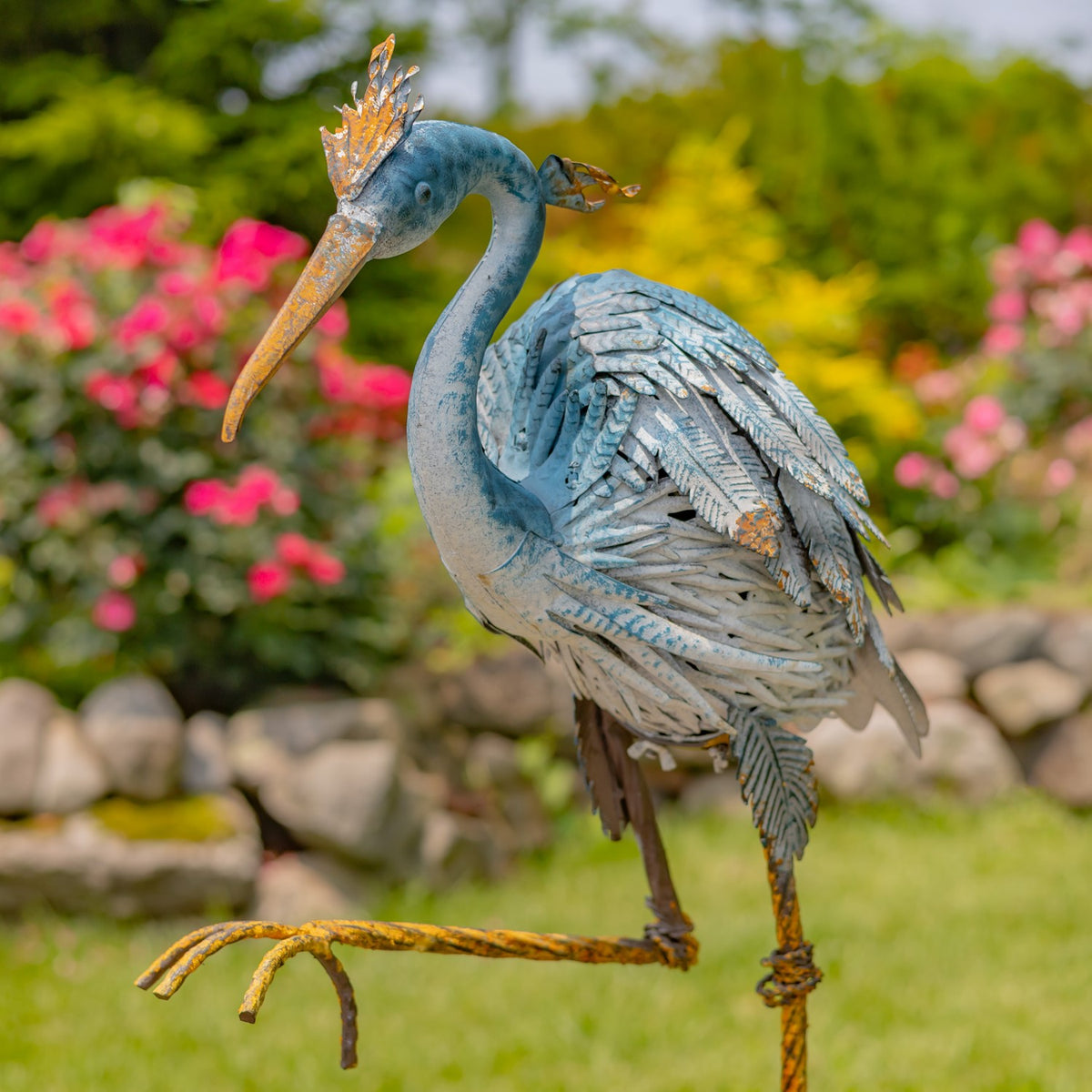 Close view of a blue and grey heron figurine with one leg raised