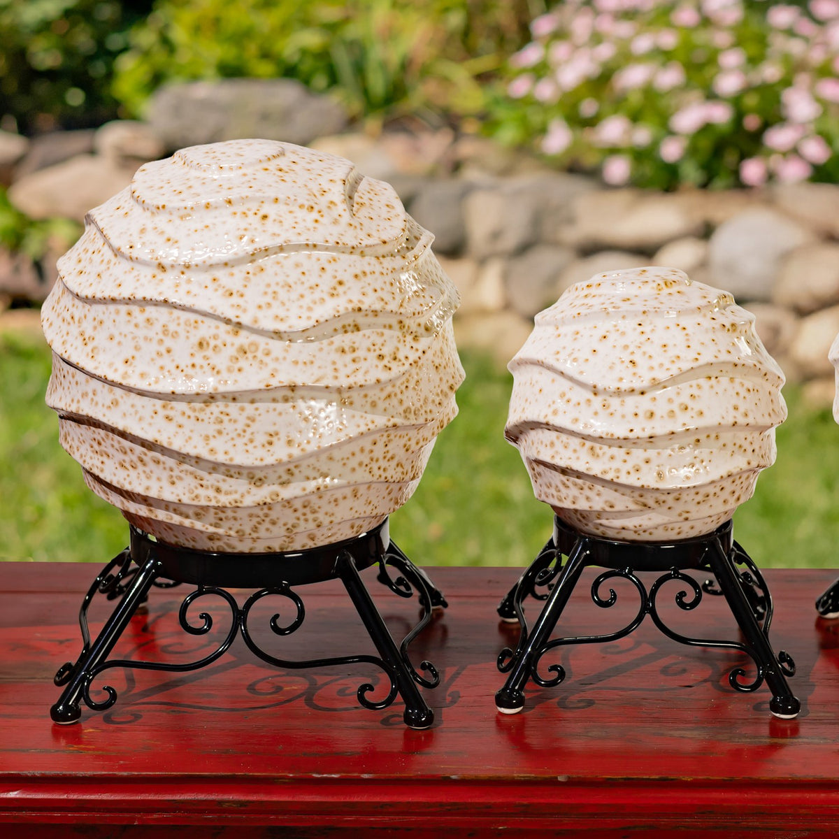 Two speckled ivory globes in ornate black stands, with the larger globe on the left.