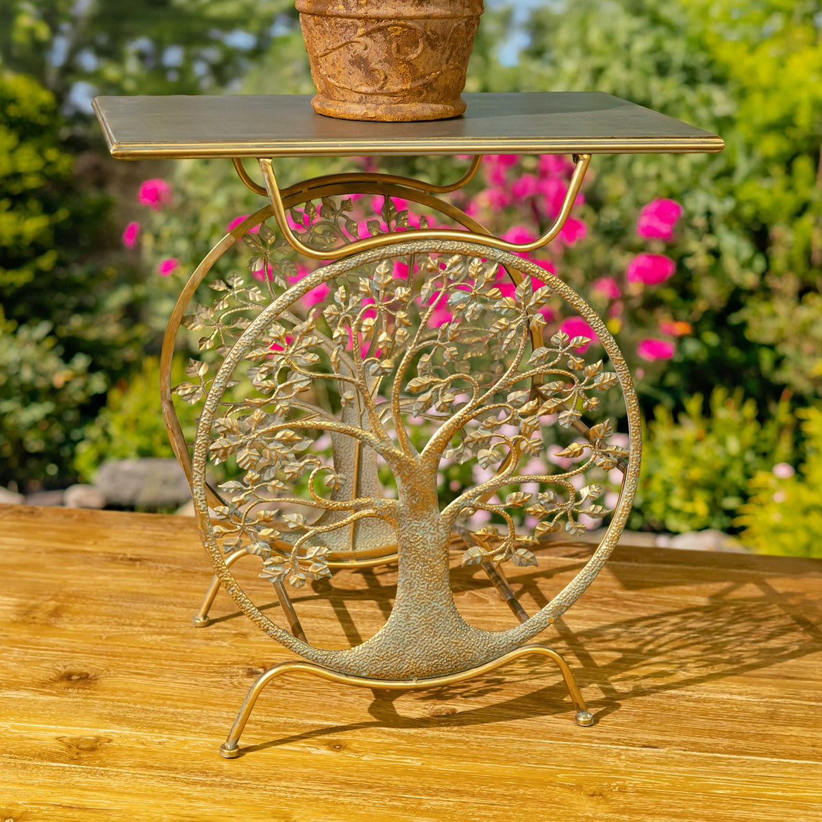 A single gold plant stand with a rectangular top and circular tree motif, shown with a potted plant.