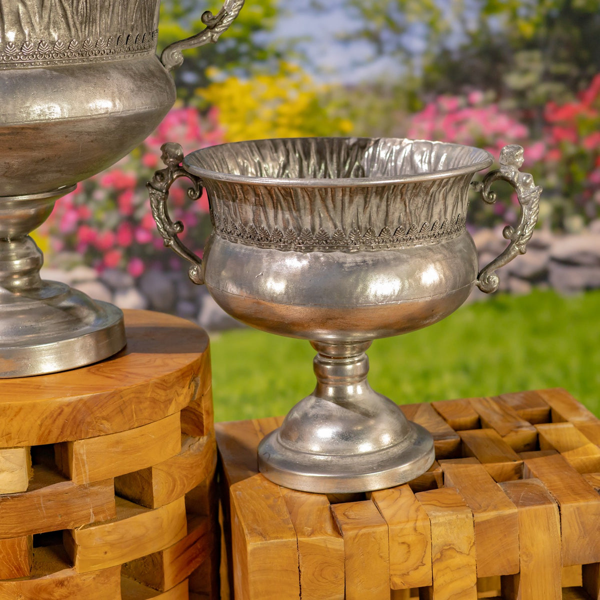 Smaller silver urn with decorative handles and a fluted rim, displayed beside part of the larger urn.