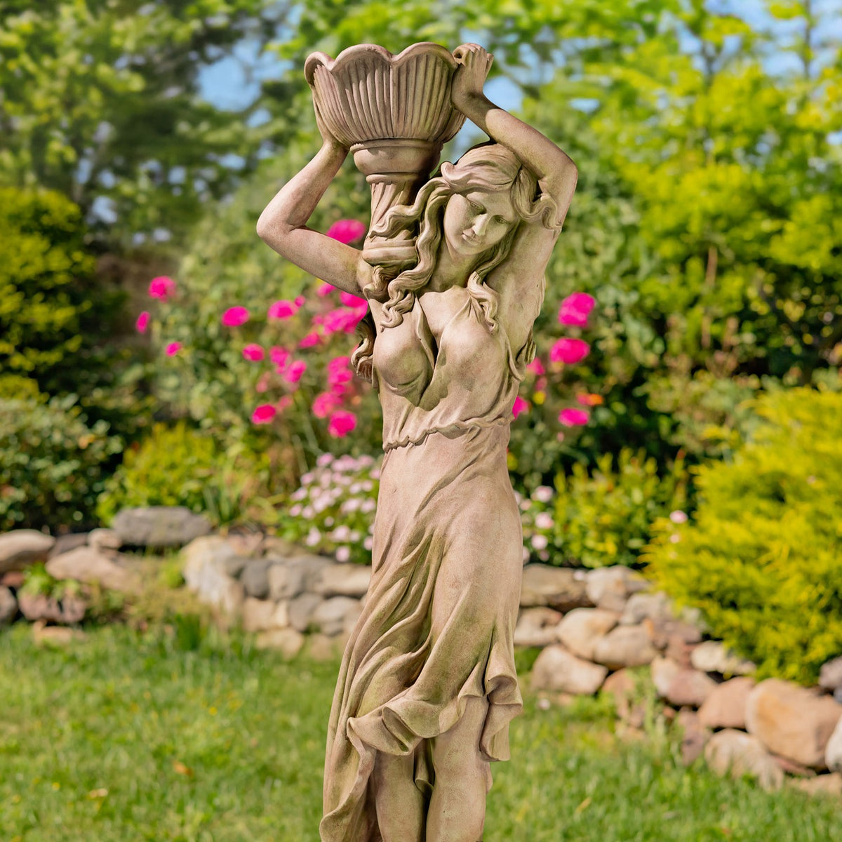 A closer front view of the female statue supporting an empty fluted pot above her head.
