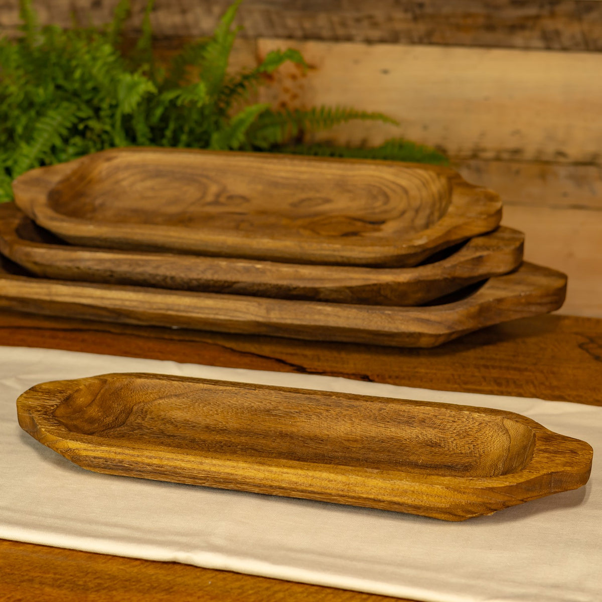 Four empty wooden trays of graduated sizes are shown, with one in front and three stacked behind.